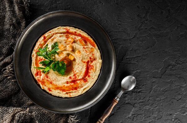 Chickpeas hummus with olive oil, paprika in a plate over dark st