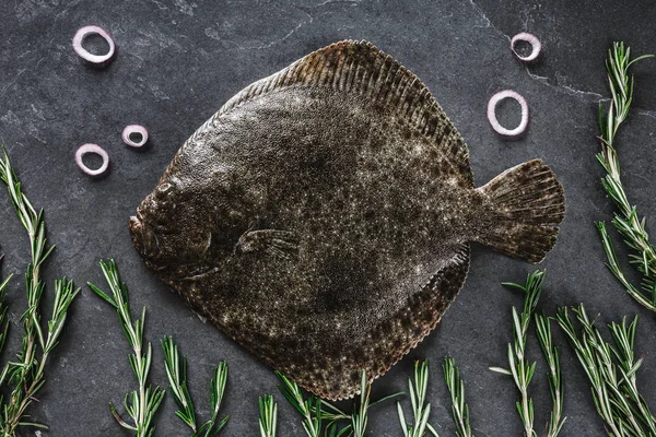 Rå hel skrubbfisk med rosmarin, lök och kryddor på mörk — Stockfoto