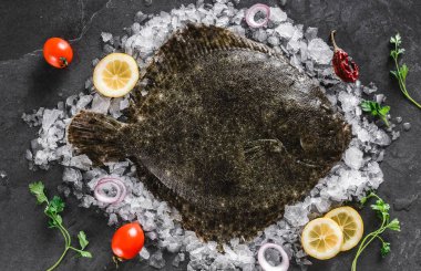 Raw whole flounder fish with spices and lemon on ice over dark s clipart