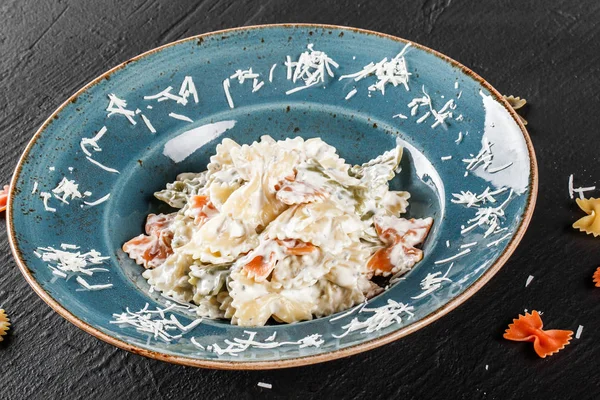 Паста Фарфалле в сливочном сырном соусе в тарелке на темном камне b — стоковое фото