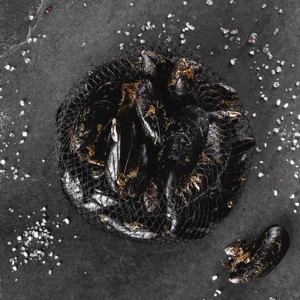 Frische rohe Miesmuscheln im Fischernetz mit Algen und Salz auf Schiefer — Stockfoto