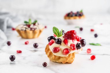 Hafif mermer arka plan üzerinde muhallebi ve çilek ile ev yapımı kek eclairs veya profiteroles. Tatil tatlısı, yakın çekim