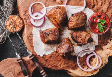 Izgara et ya da şiş kebap, ahşap tahtada domates soslu shashlik koyu taş arka planda. Üst görünüm