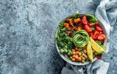 Fırında patates, nohut, brokoli, domates, yeşillik, avokado, açık mavi arka planda bezelye filizi ve peçete. Sağlıklı vejetaryen yemekleri, temiz yemek, perhiz, üst manzara.