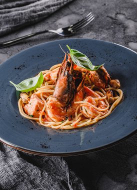 Deniz ürünleri ile Makarna spagetti, langoustine, midye, istiridye, karides, koyu gri arka plan üzerinde plaka otlar ile sos somon fileto. İtalyan yemekleri, en iyi manzara