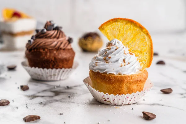 Cupcakes veya krem, açık mermer arka plan üzerinde portakal ve şeker dilim ile kekler. Tatil pastası kutlama, lezzetli tatlı, yakın çekim — Stok fotoğraf