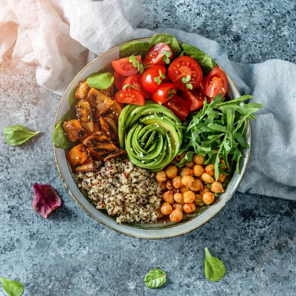 Buddha bowl salad with baked sweet potatoes, chickpeas, quinoa, tomatoes, arugula, avocado, sprouts on light blue background with napkin. Healthy vegan food, clean eating, dieting, top view — Stock Photo, Image