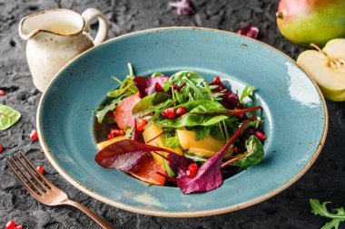 Sebzeli taze meyve salatası ve koyu arkaplanda sos. Sağlıklı yemek, vejetaryen diyeti, yakın çekim.