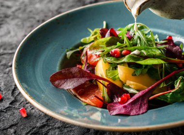 Sebzeli taze meyve salatası ve koyu arkaplanda sos. Sağlıklı yemek, vejetaryen diyeti, yakın çekim.
