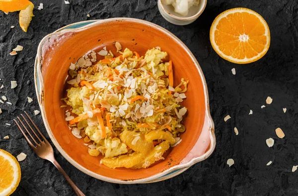 Plato vegano saludable, arroz cocido con pasas, coliflor, naranja y almendras en plato de cerámica sobre fondo oscuro. Comida saludable, alimentación limpia, dieta, vista superior — Foto de Stock