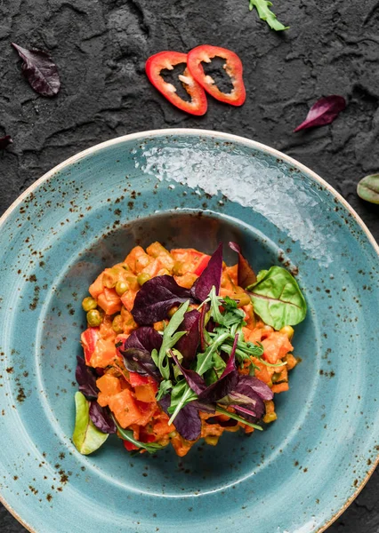 Здоровый веганский салат из тыквы с перцем и помидорами в керамической тарелке на тёмном фоне. Здоровое питание, чистое питание, диета, вид сверху — стоковое фото