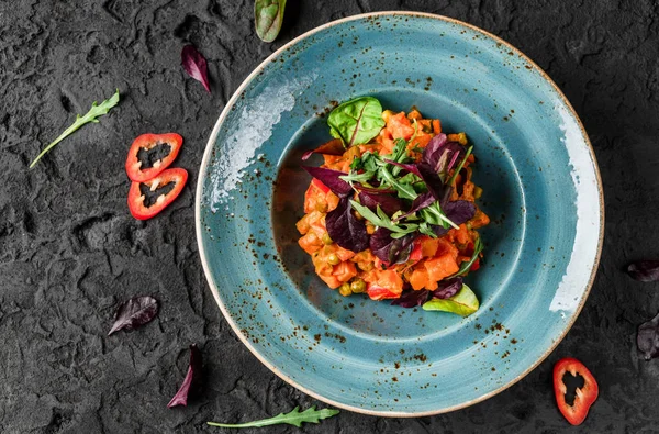 Здоровий веганський гарбузовий салат з каррі з перцем і помідорами в керамічній тарілці на темному фоні. Здорова їжа, чисте харчування, дієта, вид зверху — стокове фото
