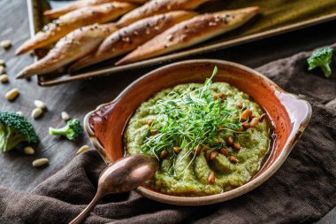 Keten peçete ile kahverengi ahşap arka plan üzerinde kruton ile kase de çam fıstığı, lahana ve zeytinyağı ile Brokoli humus. Sağlıklı vegan gıda, temiz beslenme, diyet, yakın