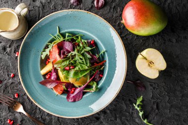 Sebzeli taze meyve salatası ve koyu arkaplanda sos. Sağlıklı yiyecekler, vejetaryen diyeti, üst manzara.