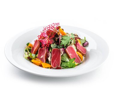 Izole beyaz arka plan üzerinde tabakta kavrulmuş ton balığı, yeşillik, biber ve sos ile sağlıklı salata. Sağlıklı yemek, temiz beslenme, diyet