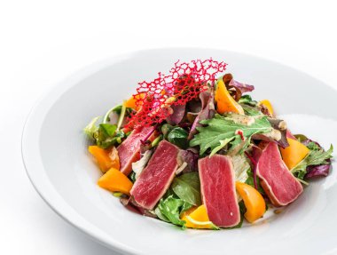 Izole beyaz arka plan üzerinde tabakta kavrulmuş ton balığı, yeşillik, biber ve sos ile sağlıklı salata. Sağlıklı yemek, temiz beslenme, diyet