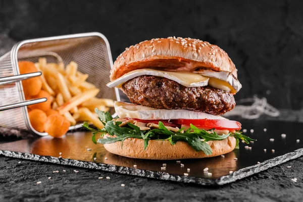Tasty burger with cheese brie, blue cheese, mozzarella, tomatoes, arugula and fried stick balls, french fries on slate black background, close up — Stock Photo, Image