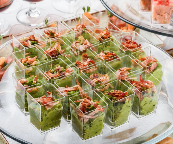 Deliciosos aperitivos con mousse verde, queso, carne en copas de vidrio en la mesa del banquete. Comida para catering, canapé y aperitivos —  Fotos de Stock