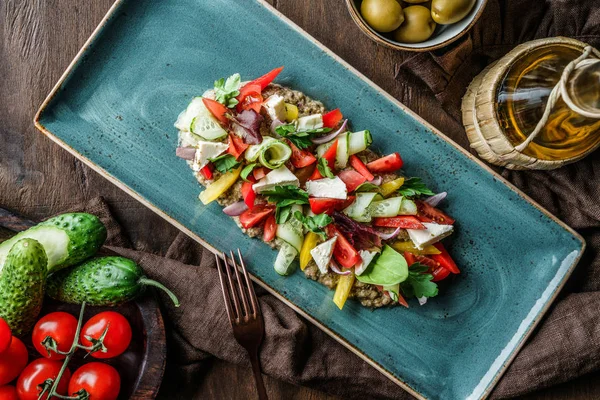 Ensalada griega de verduras ecológicas con tomates, pepinos, aceitunas, queso feta en plato sobre fondo de madera marrón. Comida saludable, alimentación limpia, dieta, vista superior — Foto de Stock