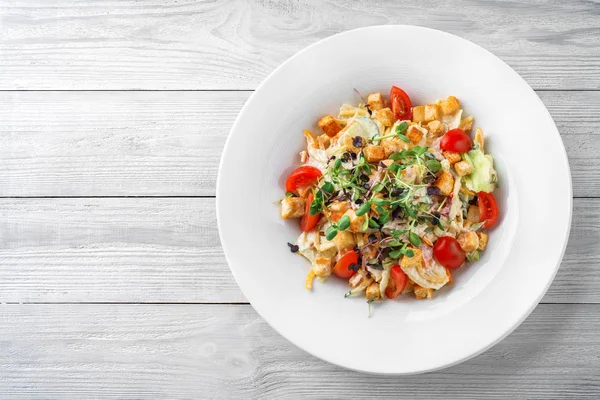 Salada Caesar com alface, tomates, brotos, croutons e molho em placa sobre fundo de madeira leve. Comida saudável, dieta vegetariana, vista superior — Fotografia de Stock