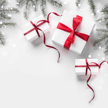 Bokeh, ışık ile beyaz kağıt arka plan üzerinde kırmızı kurdele ile hediye kutuları ile Noel köknar dalları. Xmas ve Yeni Yıl tebrik kartı. Düz yatıyordu, üstten görünüm, kış tatili