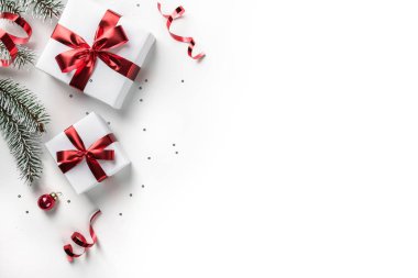Bokeh, ışık ile beyaz kağıt arka plan üzerinde kırmızı kurdele ile hediye kutuları ile Noel köknar dalları. Xmas ve Yeni Yıl tebrik kartı. Düz yatıyordu, üstten görünüm, kış tatili