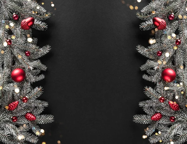 Noel ağacı dallarından, kozalaklardan, koyu arkaplanda kırmızı süslemelerden oluşan yaratıcı bir çerçeve. Xmas ve yeni yıl tatili. Düz yatış, üst görünüm