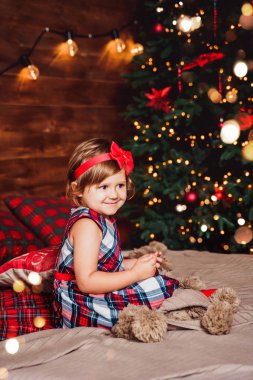 Mutlu Noeller ve yeni yıl tatilleri. Noel ağacı ve hediye kutusuyla oturma odasında xmas süsleri olan çocuk, ışık rahat bir atmosfer sağlıyor.