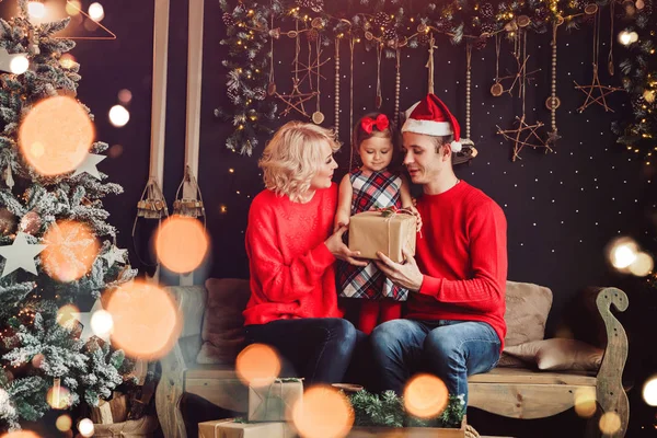 Merry Christmas and Happy New Year! Family gives present box to baby in living room decorated by christmas tree and xmas gift boxes. Portrait loving family close up, holiday — Stockfoto