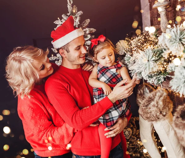 Julfamilj med barn som ler nära julgranen. Vardagsrum dekorerat med julgran och presentaskar, ger ljuset mysig atmosfär. Nyårsresor — Stockfoto