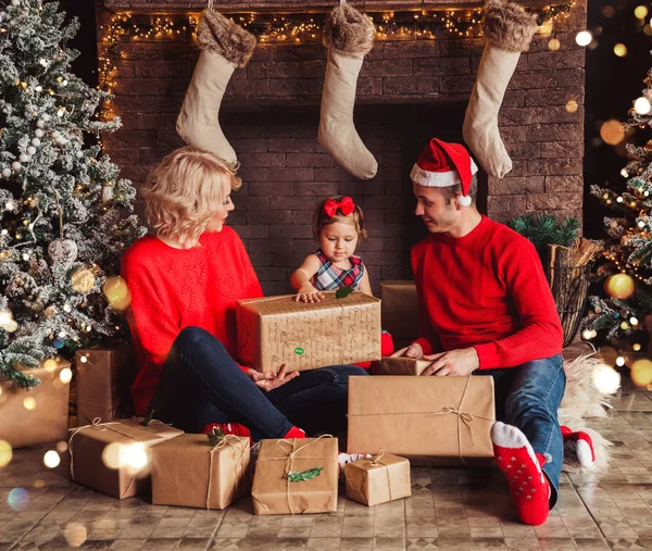 Merry Christmas and Happy New Year! Family gives present box to baby in living room decorated by christmas tree and xmas gift boxes. Portrait loving family close up, holiday — Stockfoto