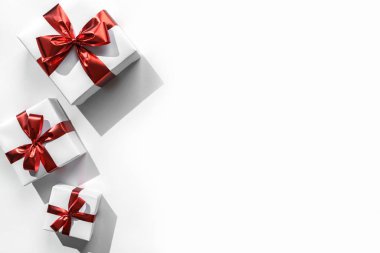 Kırmızı kurdeleli Noel hediyesi kutuları ve beyaz arka planda Bokeh 'li süslemeler. Xmas ve mutlu yıllar. Düz, üst görünüm, sert gölge.