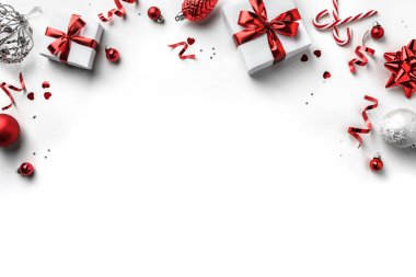 Noel ağacı dalları, kırmızı kurdeleli hediye kutuları, kırmızı süslemeler, parıltılar ve beyaz arka planda konfeti. Noel ve yeni yıl tebrik kartı, kış tatili. Düz yatış, üst görünüm