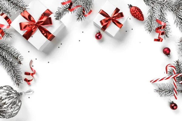 Ramas de abeto navideño, cajas de regalo con cinta roja, decoración roja, destellos y confeti sobre fondo blanco. Tarjeta de felicitación de Navidad y Año Nuevo, vacaciones de invierno. Piso tendido, vista superior —  Fotos de Stock