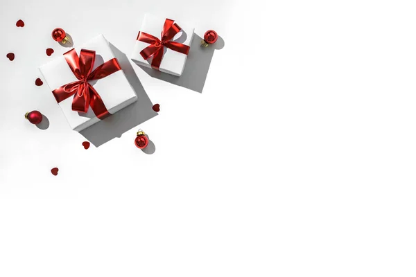 Різдвяні подарунки з червоною стрічкою, блискітками, конфетті та прикрасами на білому тлі. Xmas and Happy New Year. Вигляд зверху. — стокове фото