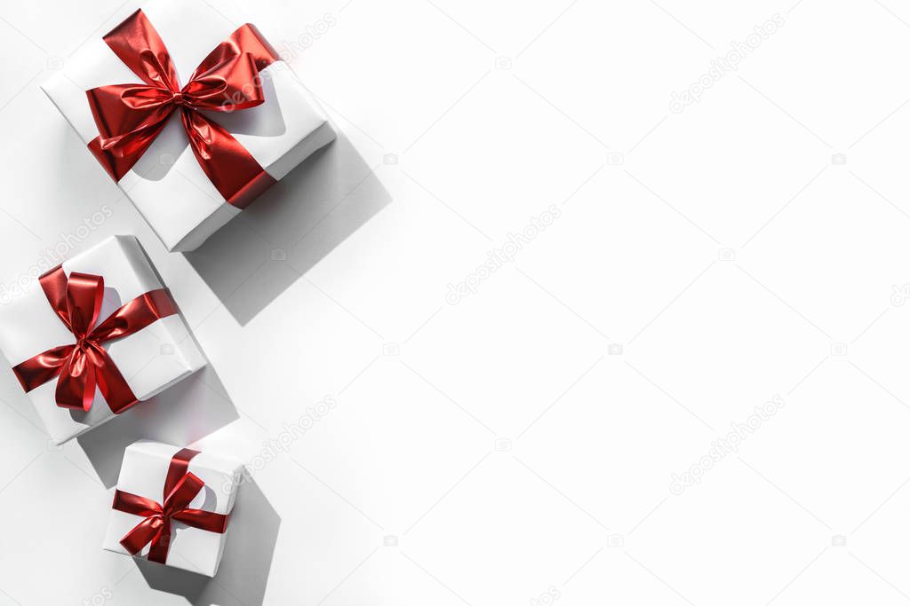 Christmas gift boxes with red ribbon and decoration on white background with bokeh, light. Xmas and Happy New Year holiday. Flat lay, top view, harsh shadow