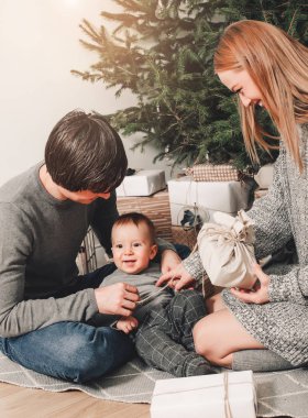 Mutlu aile çifti, dekore edilmiş Xmas ağacının arkasındaki salonda hediyeler veriyor, ışık da rahat bir atmosfer sağlıyor. Yeni yıl ve mutlu noeller