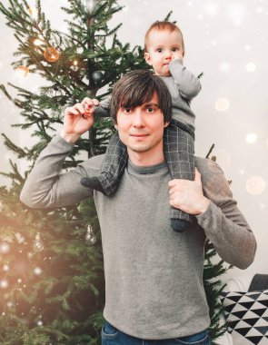 Mutlu Noeller ve mutlu yıllar! Baba ve oğul oturma odasında gülümsüyor. Noel ağacı ve Noel hediyesi kutularıyla süslenmiş. Portre seven aile yakın çekim, tatil