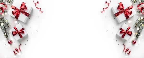 Ramos de abeto de Natal, caixas de presente com fita vermelha, decoração vermelha, brilhos e confetes no fundo branco. Xmas e cartão de saudação de Ano Novo, férias de inverno. Deitado plano, vista superior — Fotografia de Stock