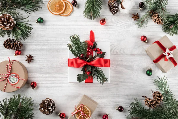 Kreativa ram av jul fir grenar på vit trä bakgrund med röd dekor, kottar. Xmas och nyår tema. Platt lekmanna, top view — Stockfoto