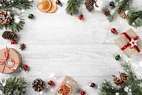 Marco creativo hecho de ramas de abeto de Navidad sobre fondo de madera blanca con decoración roja, conos de pino. Tema Navidad y Año Nuevo. Piso tendido, vista superior —  Fotos de Stock