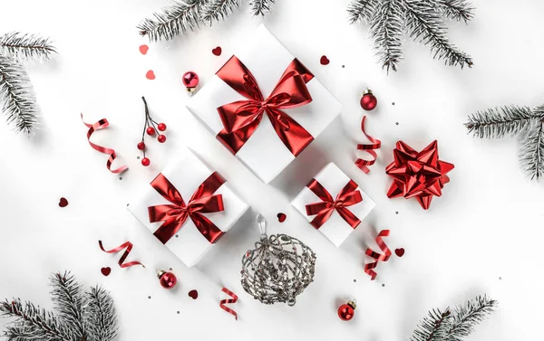 圣诞冷杉枝条，红丝带礼品盒，红色装饰，闪光和白色背景的彩霞。圣诞和新年贺卡,寒假.平躺在地上，俯瞰四周 — 图库照片