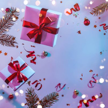 Uçan süslemeler, hediye kutuları, köknar dalları, toplar, ışıltılar ve renkli neon ve mor arka planda konfetilerden oluşan Noel kartı. Xmas ve yeni yıl tatili, bokeh, ışıklar. Seçici odak