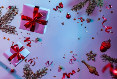 Uçan süslemeler, hediye kutuları, köknar dalları, toplar, ışıltılar ve renkli neon ve mor arka planda konfetilerden oluşan Noel kartı. Xmas ve yeni yıl tatili, bokeh, ışıklar. Seçici odak