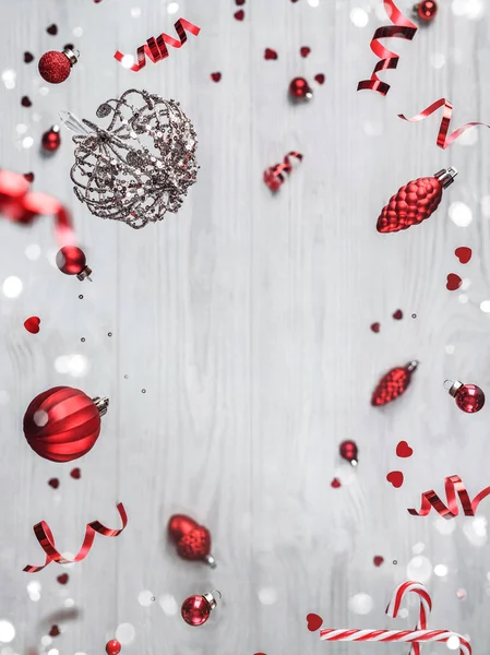 Δημιουργικό πλαίσιο από ιπτάμενες χριστουγεννιάτικες διακοσμήσεις, κουτιά δώρων, κλαδιά ελάτης, κόκκινη διακόσμηση, αστράφτει και κομφετί σε ξύλινο φόντο. Χριστούγεννα και Πρωτοχρονιά διακοπές, bokeh, φως. Επιλεκτική εστίαση — Φωτογραφία Αρχείου