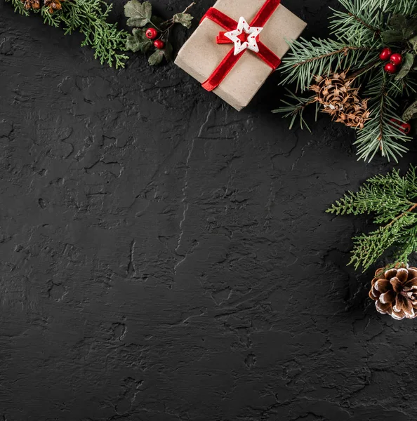 Ramos de abeto de Natal, cones de pinheiro e presentes no fundo escuro. Tema de Natal e Ano Novo. Deitado plano, vista superior — Fotografia de Stock