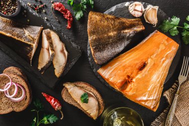 Baharatlı, ekmek ve yağlı füme beyaz fileto. Koyu taş arka planda tahtada. Deniz ürünleri, üst manzara.