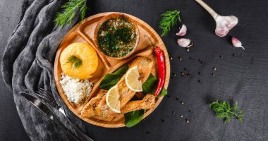 Izgara fileto, peynir ve baharat soslu nefis polenta siyah taş zemin üzerinde tahtayı keser. Sıcak balık tabakları. Üst manzara, düz uzanma