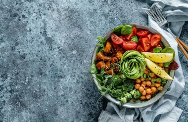 Fırında patates, nohut, brokoli, domates, yeşillik, avokado, açık mavi arka planda bezelye filizi ve peçete. Sağlıklı vejetaryen yemekleri, temiz yemek, perhiz, üst manzara.