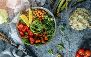 Fırında patates, nohut, brokoli, domates, yeşillik, avokado, açık mavi arka planda bezelye filizi ve peçete. Sağlıklı vejetaryen yemekleri, temiz yemek, perhiz, üst manzara.